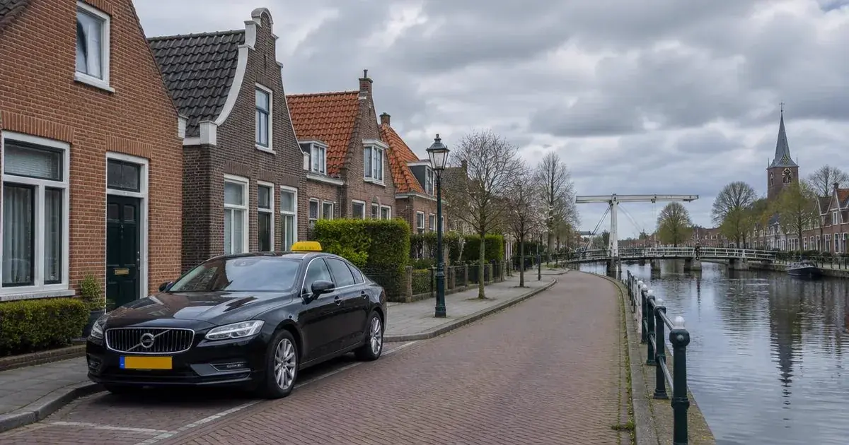 Taxi Moordrecht met vaste prijs Taxi in Moordrecht langs een vaart met bakstenen huizen