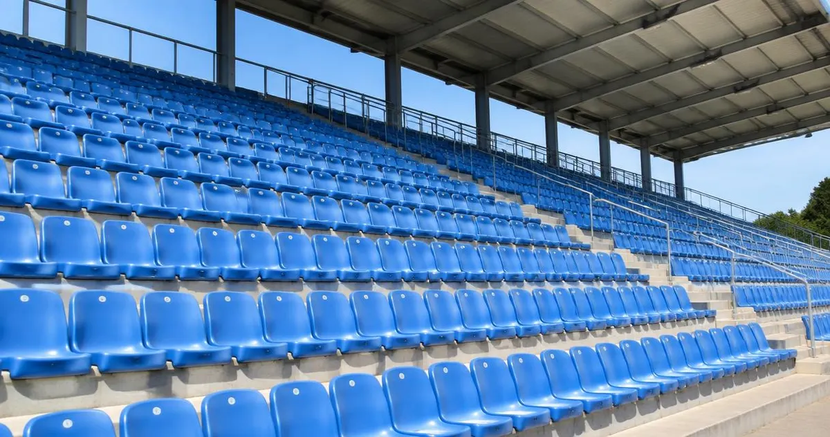 Empty sports stands with blue seats in daylight