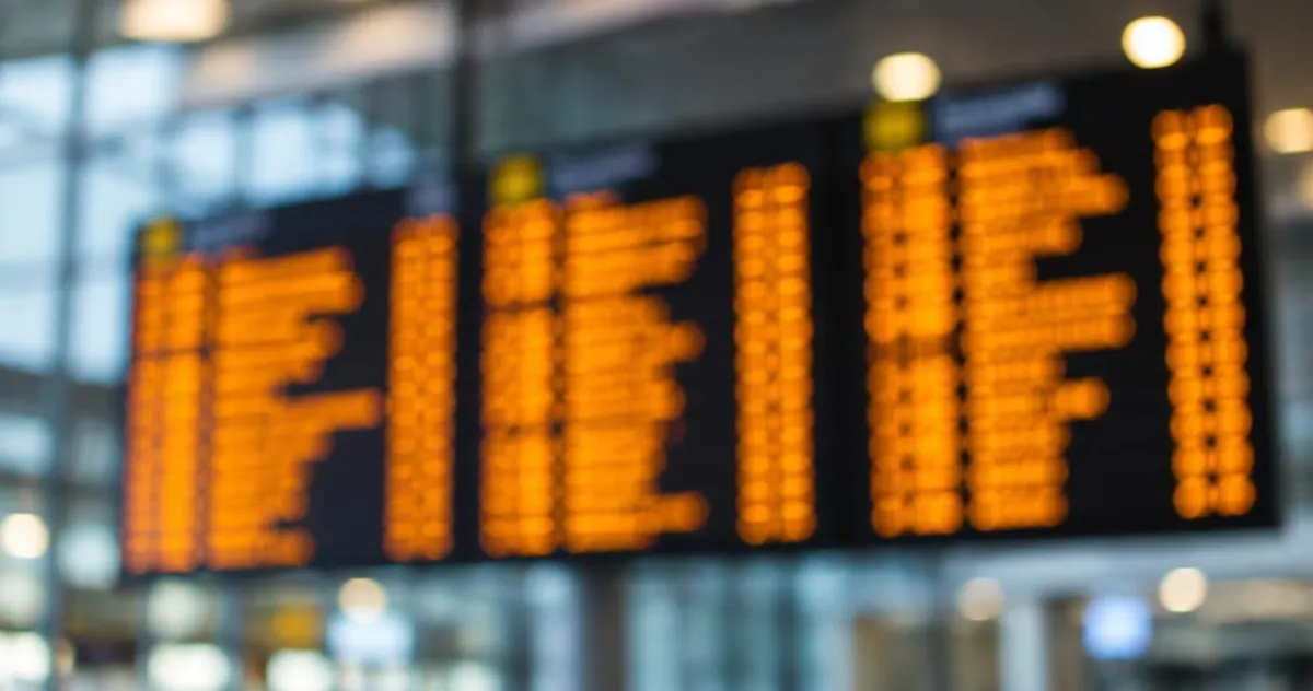 Vertrekbord op een luchthaven met onscherpe tekst en oranje lampjes